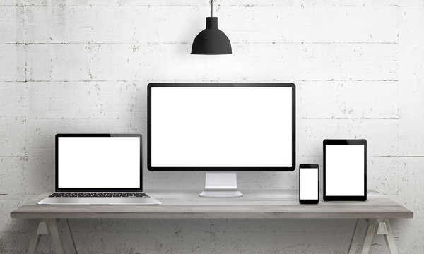 Responsive web site mockup. Computer display, laptop, tablet and smart phone on desk with isolated, blank, white screen for design presentation.