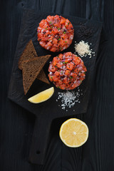 Above view of salmon tartare over black wooden background, studio shot