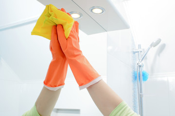 A woman polishing glass using a cleaning sponge and rubber gloves cleaning a mirror with a spray cleaner