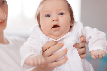Young mother and newborn baby in white bedroom