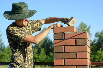 Bricklayer Worker Installing Red Clinker Blocks and Caulking Brick Masonry Joints Exterior Wall...