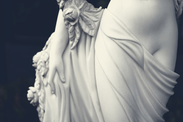 White female figure sculpture in dark tone.