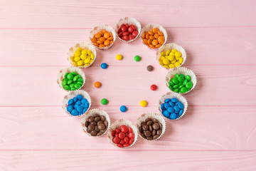 Multicolored candies on a pink wooden background
