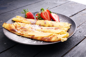 Crepes with jam, strawberries and sugar powder. Homemade pancakes, delicious breakfast