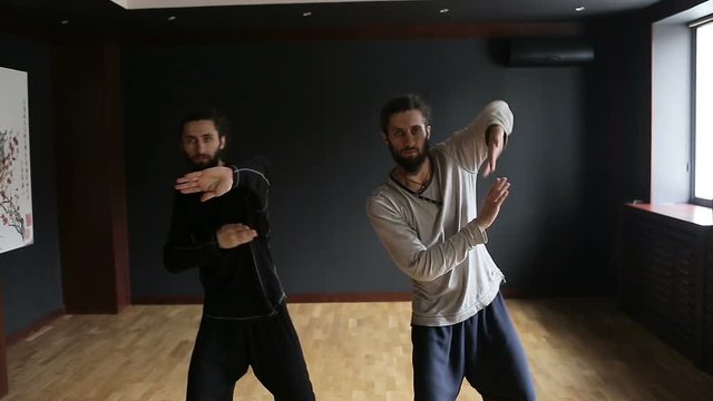 Twins brothers practice Tai Chi in the training hall