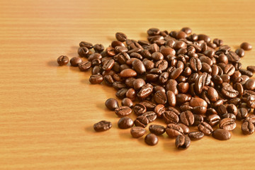 scattered roasted coffee beans on wooden table background