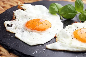 Afwasbaar Fotobehang Spiegeleieren gebakken eieren met basilicum peper en zout