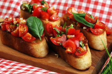 Tasty savory tomato Italian appetizers, or bruschetta, on slices of toasted baguette garnished with basil