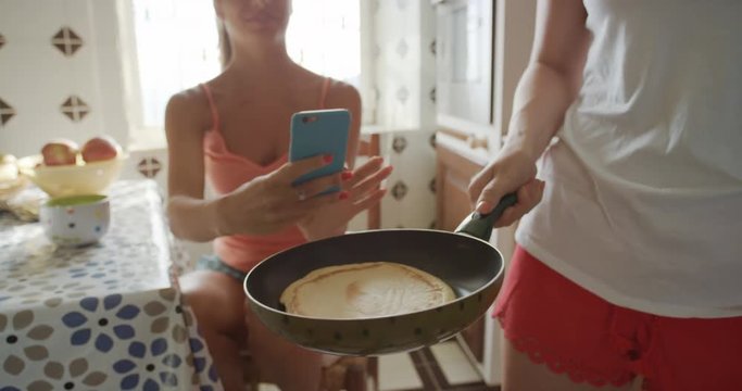 Best Friends making home made Pancakes girl taking photo using smart phone Lifestyle Woman at home sharing on social media