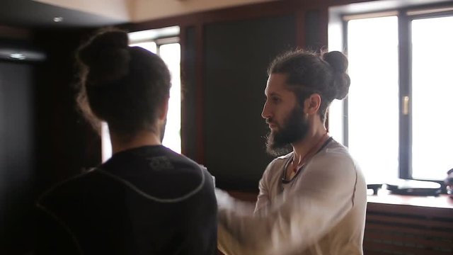 Twin brothers practicing tai chi blows in the training hall
