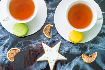 Still life with gingerbread nad macarons and tea on the black marble background