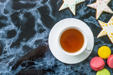 Still life with gingerbread nad macarons and tea on the black marble background