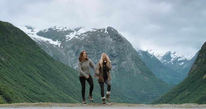 Group of people dancing silly freestyle dance outdoors celebrating hiking at top of snow capped mountain Crazy dancer girl having fun enjoying nature celebrating vacation travel adventure Norway