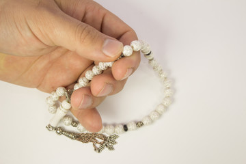 Muslim male hands holding rosary on white background