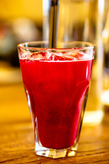 Dark red drink in a glass is on the table in the restaurant.