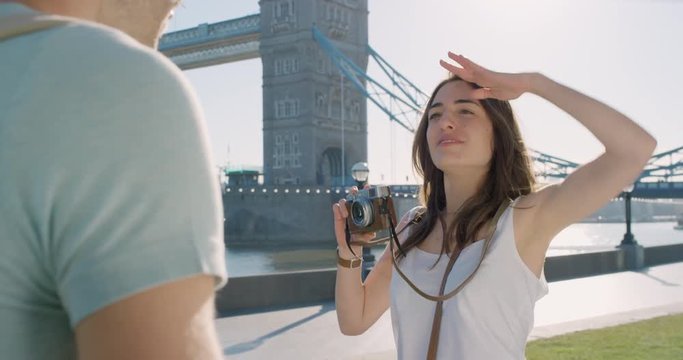 Tourist couple taking photograph of each other while sightseeing making funny faces enjoying European summer holiday travel vacation adventure
