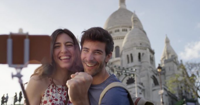 Tourist couple taking selfie photograph Sacre Coeur Paris with smartphone in city enjoying summer holiday European vacation travel adventure 