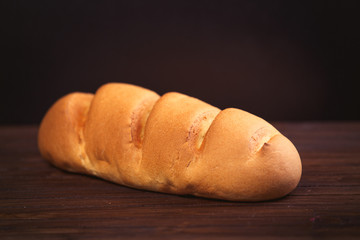 photo of tasty fresh bread loaf on the wonderful brown wooden background