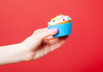 photo of female hand holding cupcake on the wonderful red background
