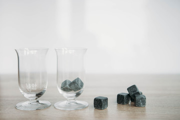 Stones for cooling whiskey and glases tulup on light wooden background