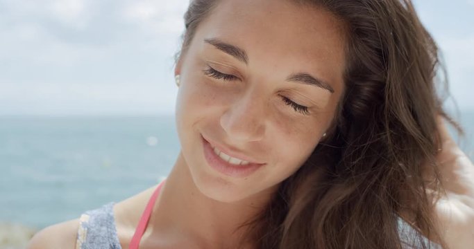 Close up portrait of Beautiful Young Woman smiling  hair blowing in wind on tropical beach slow motion