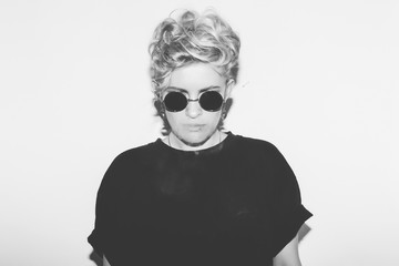 Stylish fashion sexy blonde bad girl in a black t-shirt and rock sunglasses. Dangerous rocky emotional woman. white toned. background, not isolated