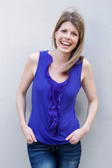 woman standing with her hands in pocket and laughing