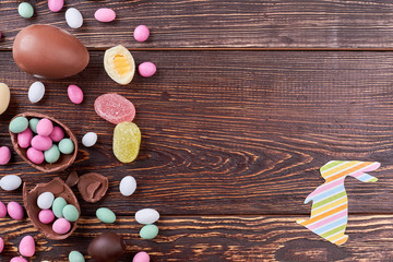 Sweets on brown wood, copyspace. Colorful paper bunny cutout.