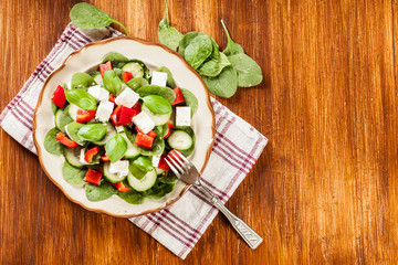 Fresh spinach salad with feta, cucumber and red paprika on a pla