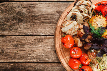 Wooden platter with grilled vegetables on rustic wooden table, top view. Free space for text. Restaurant menu photo. Healthy lifestyle, vegetarian cuisine concept