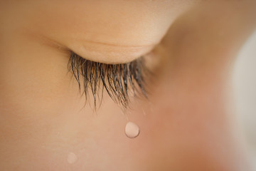 Closed eyelid child close up with a tear on the eyelashes. A tear runs down his cheek. The baby is crying - 142903717
