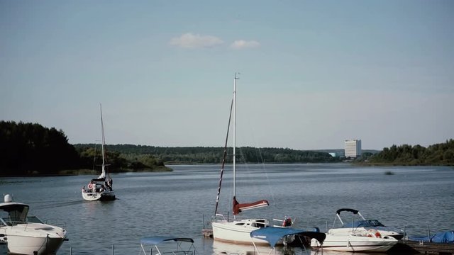 View to the mooring in the summer day. Sailboards moving to the open water from the shore. Sports leisure.
