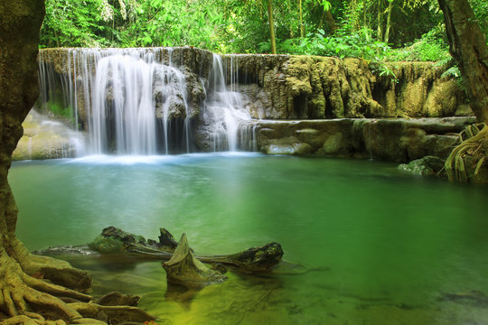 waterfall left side with clear green emerald water and rock for relax and refreshing cool with tree and root in the jungle or forest at Huay Mae Khamin waterfall for nature landscape and background
