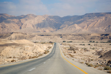 Road in the desert of Israel. Deserted trail with a desert landscape. - obrazy, fototapety, plakaty
