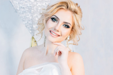 Portrait of a beautiful bride who is holding a wedding dress in a bright room