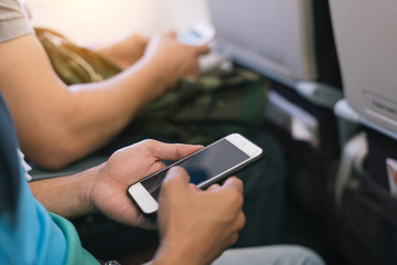Passenger using smart phone on the airplane in selective focus.