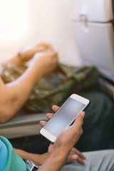 Passenger using smart phone on the airplane in selective focus.