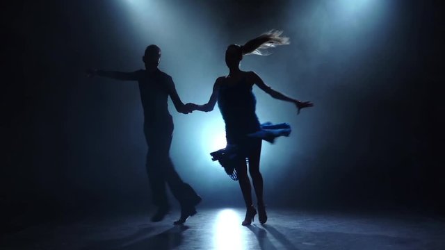 Professional couple of rumba dancers posing in smoky, slow motion
