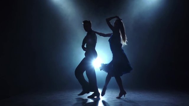 Professional couple of latino dancers posing in smoky, slow motion
