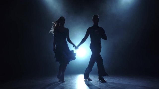 Professional couple of ballroom-sport dancers posing in smoky, slow motion