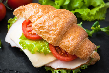 Croissant sandwich with ham, cheese, lettuce and tomato