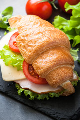 Croissant sandwich with ham, cheese, lettuce and tomato
