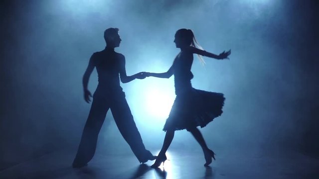 Graceful couple of latinamerican dancers posing in smoky, slow motion
