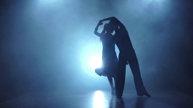 Graceful couple of ballroom dancers posing in smoky, slow motion