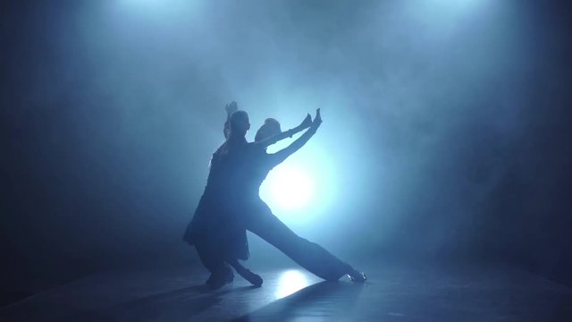 Graceful couple of salsa dancers posing in smoky, slow motion