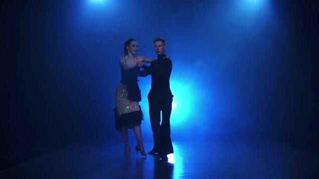 Happy couple dancing latin american in smoky studio, slow motion