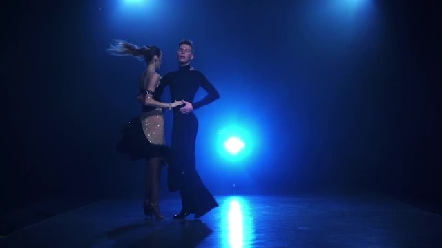Latinamerican dancing pair of professional dancers in slow motion, smoke
