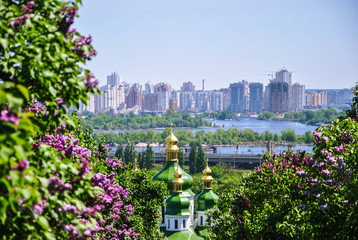 Iconic view to a monastery Vydubitsky and Dnieper River from a botanical garden of Kyiv with blooming lilac, Ukraine.;