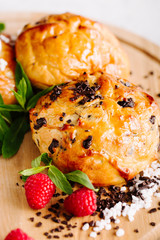 Close Up of Fresh Buns Decorated With Raspberries, Sugar And Chocolate On A Wooden Board