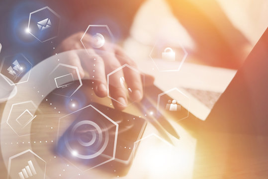 Concept of virtual screen,connections icon and digital interfaces.Closeup view of Businessman working at office on laptop.Man pointing hand on thouch screen of smartphone.Flares effect on background.
